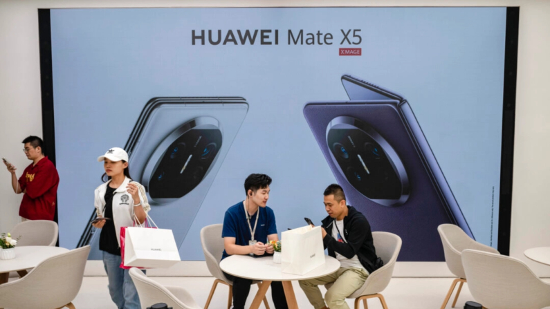 Un cliente habla con un dependiente mientras recoge un nuevo smartphone Mate 60 en una tienda insignia de Huawei después de que la compañía presentara nuevos productos en Beijing, China, el 25 de septiembre de 2023. (Kevin Frayer/Getty Images)