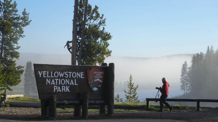 Un hombre toma una fotografía en la entrada sur del Parque Nacional Yellowstone, el 22 de junio de 2022, en Wyoming. (George Frey/Getty Images)