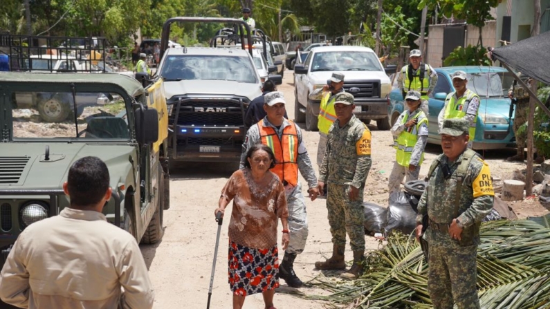 Una mujer pasa junto a las fuerzas de seguridad desplegadas para ayudar a la gente ante la llegada del huracán Beryl en Tulum, estado de Quintana Río, México, el 4 de julio de 2024. (Elizabeth Ruiz/AFP vía Getty Images)