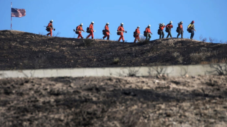 Imagen de archivo: Bomberos reclusos marchan junto a una bandera de EE. UU. mientras apagan puntos calientes de un incendio forestal en Santa Clarita, California, el 25 de octubre de 2019. (Mario Tama/Getty Images)