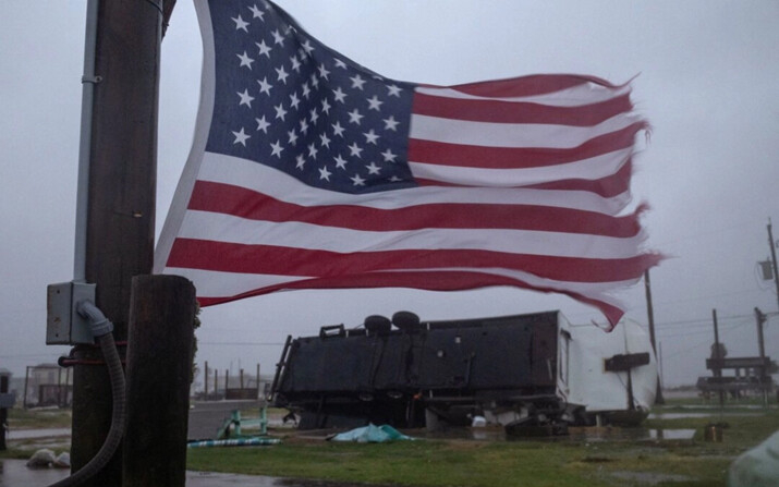 Una bandera estadounidense ondea cerca de una casa remolque que quedó volcada por los vientos del huracán Beryl en Surfside Beach, Texas, el 8 de julio de 2024. (Adrees Latif/Reuters)