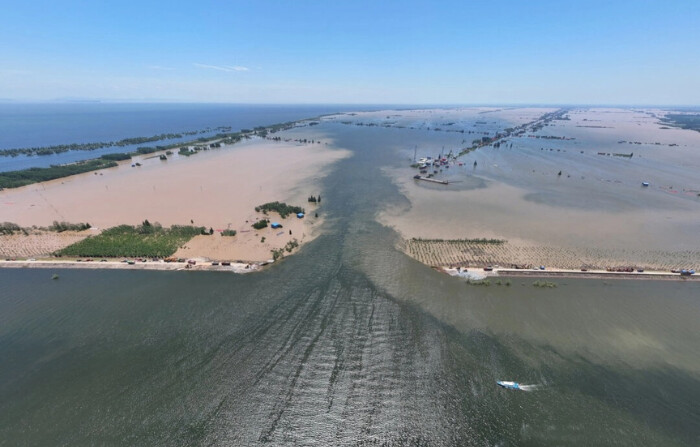 El agua fluye a través de una brecha en el terraplén en la orilla del lago Dongting en el condado de Huarong, en la provincia central china de Hunan, el 6 de julio de 2024. (STR/AFP vía Getty Images)
