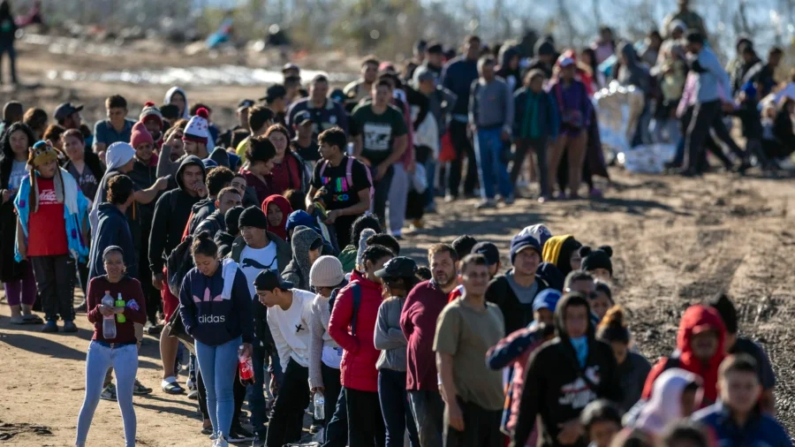 Más de 1000 inmigrantes ilegales esperan en fila para ser procesados por agentes de la Patrulla Fronteriza de Estados Unidos después de cruzar el Río Grande desde México, en Eagle Pass, Texas, el 18 de diciembre de 2023. (John Moore/Getty Images)
