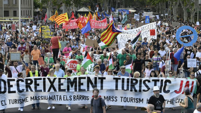 Manifestantes sostienen pancartas en las que se lee "Turism decrease" durante una protesta contra el turismo de masas en el callejón de Las Ramblas de Barcelona (España), el 6 de julio de 2024. (Josep Lago/AFP vía Getty Images)