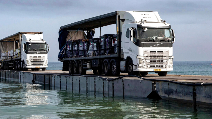 Camiones cargados de ayuda humanitaria de los Emiratos Árabes Unidos y de la Agencia de los Estados Unidos para el Desarrollo Internacional cruzan el muelle Trident antes de llegar a la playa de la Franja de Gaza el 17 de mayo de 2024. (Sargento Malcolm Cohens-Ashley/Ejército de EE.UU. vía AP)