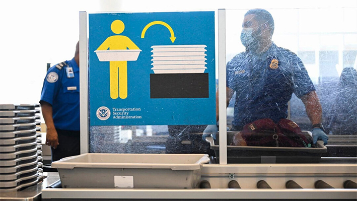 Un agente de la Administración de Seguridad en el Transporte (TSA) revisa el equipaje de mano en el Aeropuerto Internacional de Los Ángeles (LAX) en Los Ángeles, California, el 10 de agosto de 2022. (Patrick T. Fallon/AFP vía Getty Images)