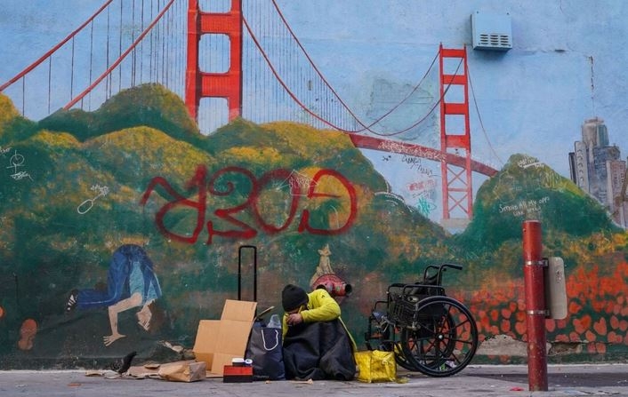 Una persona sin hogar se recuesta contra un mural del puente Golden Gate en el centro de San Francisco el 11 de noviembre de 2023. (Loren Elliott/AFP vía Getty Images)