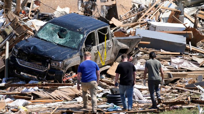 Los residentes locales caminan entre los escombros de las casas dañadas por tornados, 22 de mayo 2024, en Greenfield, Iowa. (AP Photo/Charlie Neibergall, File)