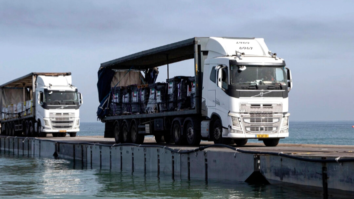 Camiones cargados con ayuda humanitaria de los Emiratos Árabes Unidos y de la Agencia de los Estados Unidos para el Desarrollo Internacional cruzan el Muelle Trident antes de llegar a la playa de la Franja de Gaza el 17 de mayo de 2024. (Sargento Malcolm Cohens-Ashley/Ejército de EE.UU. vía AP)