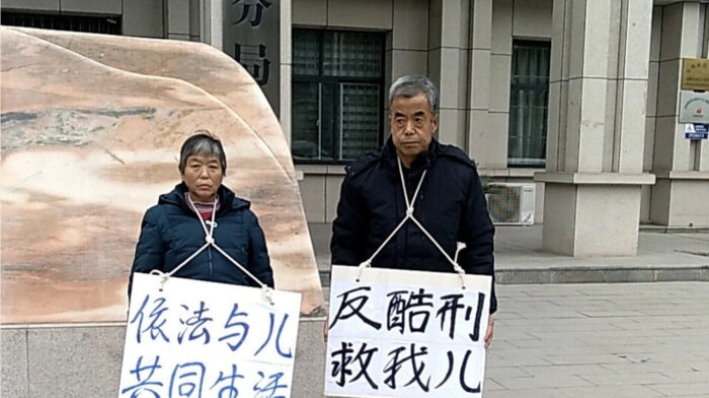 Los padres del abogado chino Chang Weiping protestan por la tortura de su hijo frente a la sucursal de Gaoxin de la Oficina de Seguridad Pública de la ciudad de Baoji, China, el 14 de diciembre de 2020. (The Epoch Times)