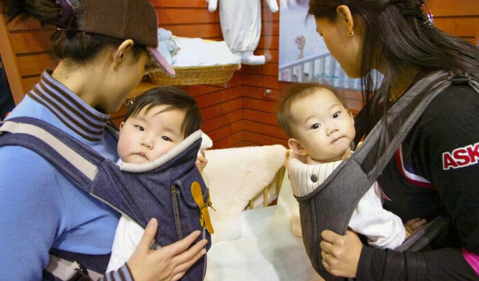 Dos madres cargan a sus bebés en una exposición sobre embarazo y maternidad en Seúl, Corea del Sur, el 17 de febrero de 2005. (Chung Sung-jun/Getty Images)