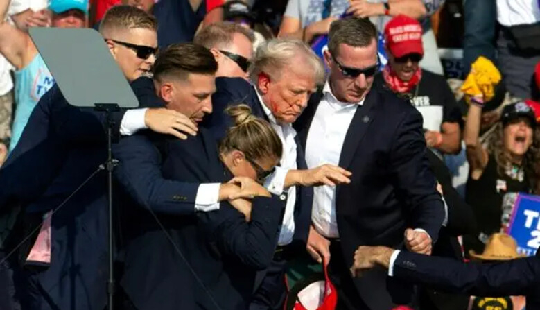 El expresidente Donald Trump con sangre en el rostro, rodeado de agentes del servicio secreto, mientras lo sacan del escenario en un evento de campaña en Butler Farm Show Inc., en Butler, Pensilvania, el 13 de julio de 2024. (Rebecca Droke/AFP vía Getty Images)