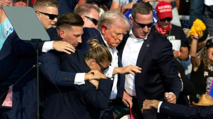 El expresidente Donald Trump con sangre en el rostro rodeado de agentes del servicio secreto mientras lo sacan del escenario en un evento de campaña en Butler Farm Show Inc. en Butler, Pensilvania, el 13 de julio de 2024. (Rebecca Droke/AFP vía Getty Imágenes)