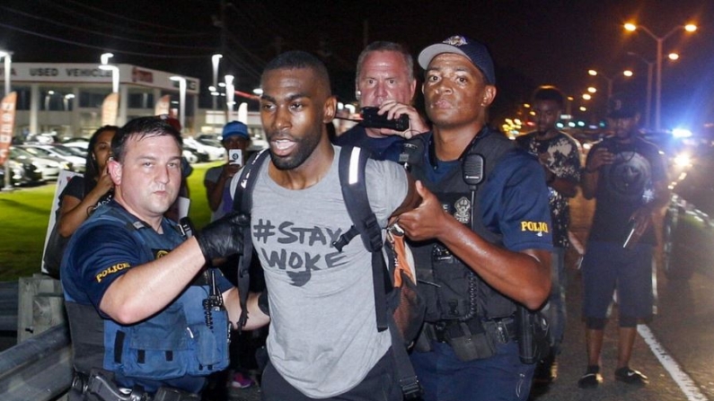 La policía detiene al activista DeRay McKesson durante una protesta a lo largo de Airline Highway, una carretera principal que pasa por delante de la sede del Departamento de Policía de Baton Rouge en Baton Rouge, La, el 9 de julio de 2016. (AP Photo/Max Becherer)