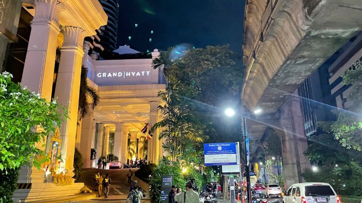 La gente camina afuera de un hotel donde varias personas fueron encontradas muertas en Bangkok, Tailandia, el martes 16 de julio de 2024. (Foto AP/Napat Kongsawad)