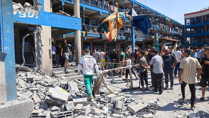 Varios palestinos examinan los daños causados por un bombardeo militar israelí contra la escuela Abu Oreiban, convertida en refugio y gestionada por el OOPS (Organismo de Obras Públicas y Socorro de las Naciones Unidas para los Refugiados de Palestina en el Cercano Oriente), donde viven palestinos desplazados internos, en el campo de refugiados de Nuseirat, en el centro de la Franja de Gaza, el 14 de julio de 2024. Eyad Baba/AFP vía Getty Images)
