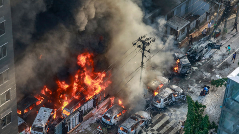 El humo se eleva desde los vehículos en llamas después de que los manifestantes les prendieran fuego cerca de la oficina de la Dirección de Gestión de Desastres, durante la protesta anti-cuota en curso en Dhaka (Bangladés) el 18 de julio de 2024. (AFP vía Getty Images)