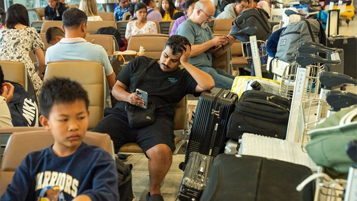 Pasajeros sentados en el aeropuerto de Suvarnabhumi con montones de equipaje en Bangkok, Tailandia, el 19 de julio de 2024. (Mailee Osten-Tan/Getty Images)