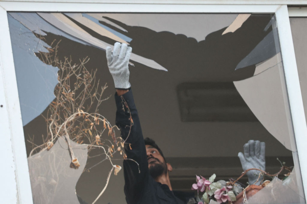 Un policía israelí recoge cristal de la ventana de un edificio que resultó dañado en una explosión que tuvo lugar en Tel Aviv el 19 de julio de 2024. (Foto de Gil Cohen-Magen/ AFP vía Getty Images)