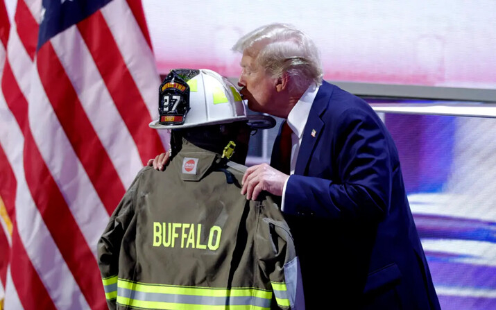 El expresidente Donald Trump besa un casco y una chaqueta de bombero que pertenecieron a Corey Comperatore, quien recibió un disparo mortal en un mitin en el que Trump sobrevivió a un intento de asesinato, mientras acepta la nominación de su partido en el último día de la Convención Nacional Republicana de 2024, en el Fiserv Forum en Milwaukee, Wisconsin, el 18 de julio de 2024. (Kamil Krzaczynski/AFP vía Getty Images)