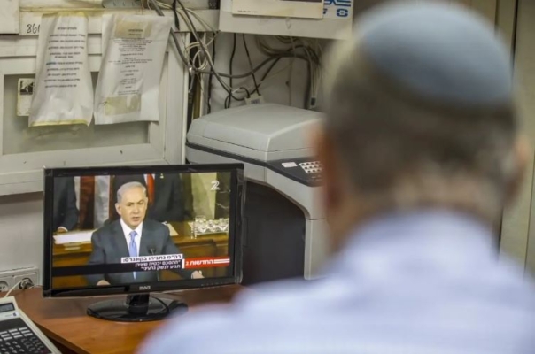 Un israelí mira desde la ciudad israelí de Netanya, el 3 de marzo de 2015, una transmisión televisiva del primer ministro israelí, Benjamín Netanyahu, dirigiéndose al Congreso de Estados Unidos en el Capitolio de Washington. (Jack Guez/AFP vía Getty Images)