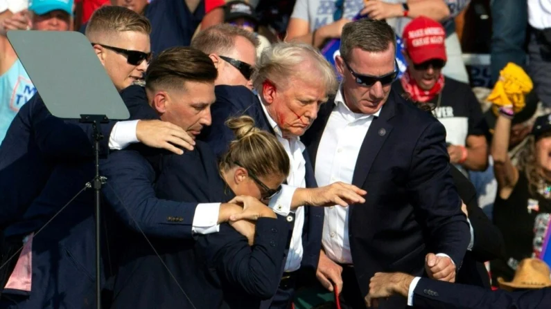 El expresidente Donald Trump con sangre en el rostro rodeado de agentes del Servicio Secreto mientras es retirado del escenario en un evento de campaña en Butler Farm Show Inc. en Butler, Pa., el 13 de julio de 2024. (Rebecca Droke/AFP vía Getty Images)