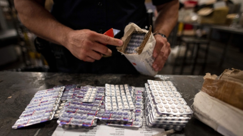 Un oficial de la División de Comercio y Carga de la Oficina de Aduanas y Protección Fronteriza de Estados Unidos encuentra pastillas de oxicodona en un paquete en la instalación del Servicio Postal de Estados Unidos del Aeropuerto John F. Kennedy, en Nueva York, el 24 de junio de 2019. (JOHANNES EISELE/AFP via Getty Images)