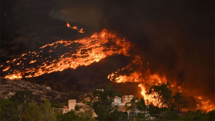 Columnas de humo suben mientras el fuego salvaje se acerca a una casa durante el incendio Fairview cerca de Hemet, California, en el condado de Riverside el 7 de septiembre de 2022. (Patrick T. Fallon/AFP)
