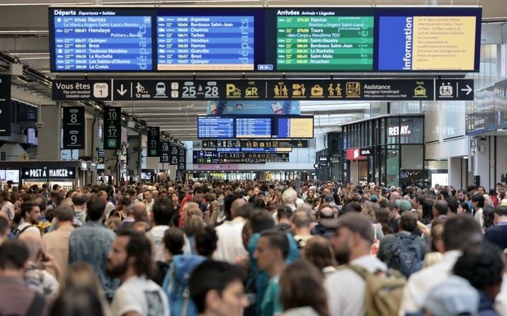 Los pasajeros se reúnen alrededor de los tableros de salida y llegada en la estación de tren Gare Montparnasse como la red ferroviaria de alta velocidad de Francia fue golpeado por actos vandálicos que interrumpen el sistema de transporte horas antes de la ceremonia de apertura de los Juegos Olímpicos de París 2024, en París el 26 de julio de 2024. (Thibaud Moritz/AFP vía Getty Images)