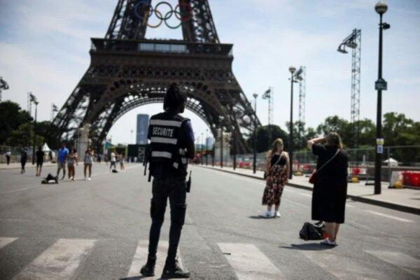 Un oficial de seguridad observa a la gente tomarse fotografías frente a la Torre Eiffel en los Juegos Olímpicos de Verano de 2024, en París, Francia, el 20 de julio de 2024. (Thomas Padilla/Foto AP)