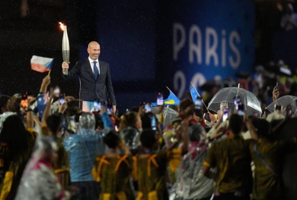 El exfutbolista francés Zinedine Zidane sostiene la antorcha olímpica durante la ceremonia de inauguración de los Juegos Olímpicos de París 2024 en París, Francia, el 26 de julio de 2024. (Xu Chang-Pool/Getty Images)