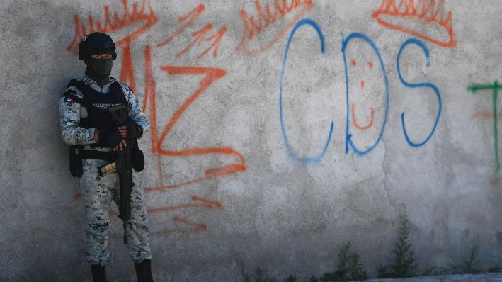 Un soldado mexicano monta guardia junto a unos grafitis del narcotraficante Mayo Zambada (MZ) y del grupo criminal "Cártel de Sinaloa" (CDS), en el poblado Palmas Altas, municipio de Jerez de García Salinas, estado de Zacatecas, México, el 14 de marzo de 2022. (PEDRO PARDO/AFP vía Getty Images)