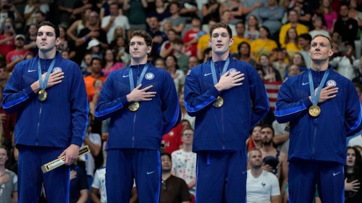 El equipo de relevos de 4x100 metros de estilo libre masculino de los Estados Unidos se encuentra en el podio después de ganar la medalla de oro en los Juegos Olímpicos de Verano de 2024, el sábado 27 de julio de 2024, en Nanterre, Francia. (Foto AP/Matthias Schrader)