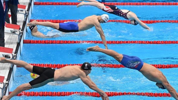 Desde arriba, la estadounidense Lydia Jacoby, el chino Yan Zibei, el italiano Nicolo Martinenghi y el ruso Kirill Prigoda se zambullen para competir en su tramo de la final de la prueba de natación de relevos mixtos 4x100 metros combinados durante los Juegos Olímpicos de Tokio 2020 en el Centro Acuático de Tokio en Tokio el 31 de julio de 2021. (ATTILA KISBENEDEK/AFP vía Getty Images)