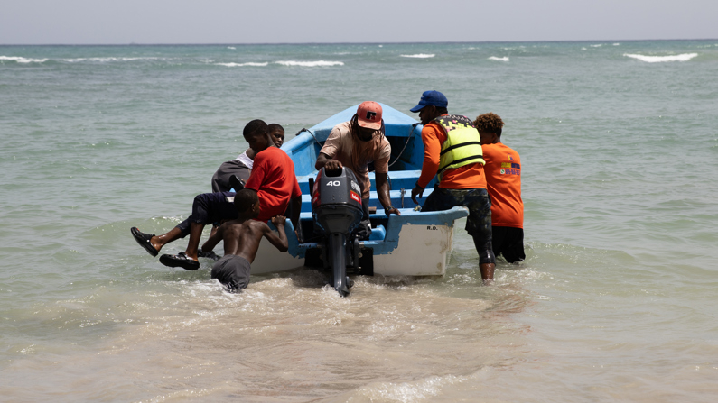 Personas participan en un operativo de búsqueda y rescate de un naufragio este sábado, en la playa Guayacanes, República Dominicana, 27 de julio de 2024. (EFE/Orlando Barría)