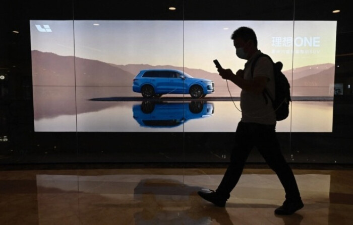 Un hombre pasa junto a una valla publicitaria que muestra un nuevo modelo Li Xiang One del fabricante chino de coches eléctricos Li Auto Inc. en un centro comercial en Beijing el 12 de agosto de 2021. (JADE GAO/AFP vía Getty Images)
