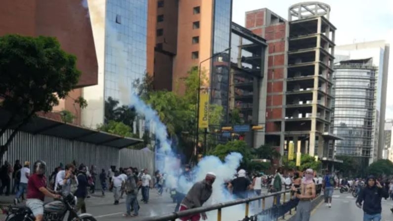 Un manifestante lanza hacia atrás un bote de gas lacrimógeno mientras partidarios de la oposición venezolana protestan en Caracas, Venezuela, el 29 de julio de 2024. (Alexandre Meneghini/Reuters)