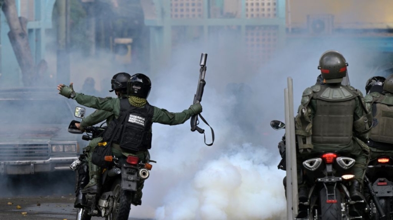 Miembros del escuadrón antidisturbios de la Guardia Nacional Bolivariana (GNB) cabalgan entre gases lacrimógenos en el barrio de Chacao mientras opositores al líder venezolano Nicolás Maduro participan en una manifestación, en Caracas, el 30 de julio de 2024. (Yuri Cortez/AFP vía Getty Images)