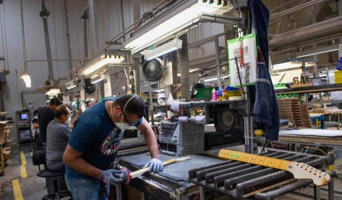 Un constructor lija el mástil de una guitarra en la fábrica de Fender en Corona, California, el 6 de octubre de 2022. (Valerie Macon/ AFP)