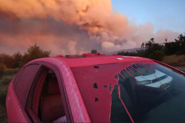 El retardante de incendios Phos-Chek recubre un vehículo durante el incendio Nixon Fire, que tiene órdenes de evacuación. Un bombero trabaja en la zona cerca de Aguanga del condado de Riverside, California, el 29 de julio de 2024. (Mario Tama/Getty Images)