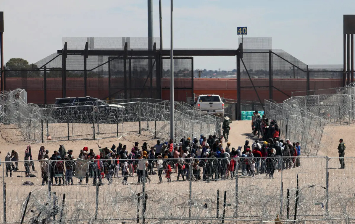 Inmigrantes ilegales hacen fila para ser trasladados por la Patrulla Fronteriza de Estados Unidos después de haber cruzado el río Bravo en El Paso, Texas, visto desde Ciudad Juárez, estado de Chihuahua, México, el 18 de abril de 2024. (Herika Martinez/AFP vía Getty Images)