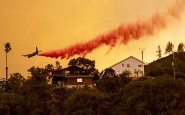 Un avión lanza retardante de fuego sobre las casas mientras las llamas del incendio LNU Lightning Complex arrasan la zona de Spanish Flat en Napa, California, el 18 de agosto de 2020. (Josh Edelson/AFP vía Getty Images)