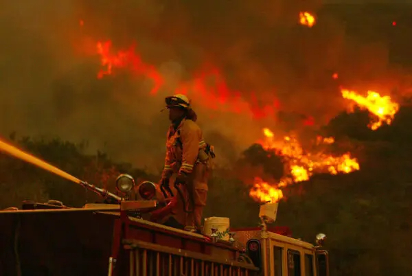 Un bombero lucha contra una parte del Cedar Fire utilizando un chorro de agua desde lo alto de un camión de bomberos cerca de Lakeside, en San Diego, el 27 de octubre de 2003. (Donald Miralle/Getty Images)