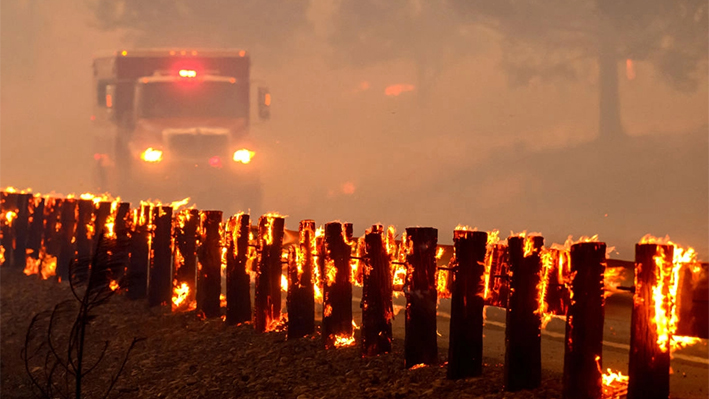 Un camión de bomberos pasa junto a las barandillas de la autopista en llamas mientras el incendio de Park sigue ardiendo cerca de Paynes Creek en el condado de Tehama, California, el 26 de julio de 2024. (Josh Edelson/AFP vía Getty Images)