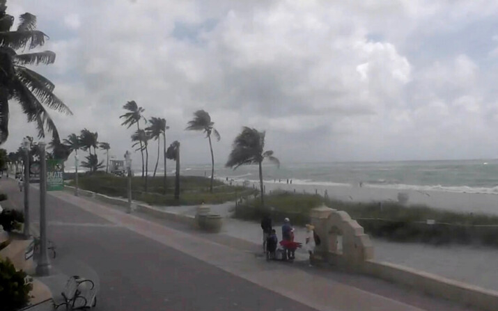 La gente camina por una playa de Hollywood mientras la tormenta tropical Debby avanza por el Golfo de México hacia Florida, en Hollywood, Florida, el 4 de agosto de 2024. (WPLG vía AP)