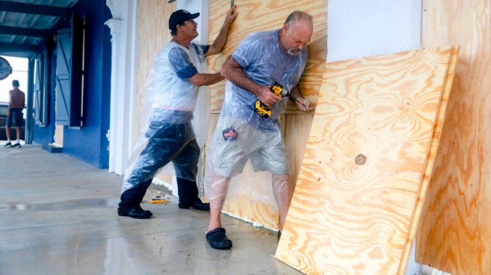 Trabajadores colocan contrachapado sobre las ventanas de un negocio mientras se preparan para la posible llegada de la tormenta tropical Debby, que se fortalece a medida que avanza por el Golfo de México, en Cedar Key, Florida, el 4 de agosto de 2024. (Joe Raedle/Getty Images)