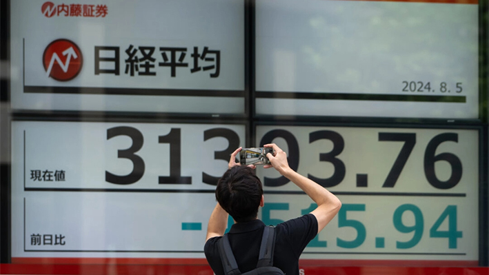 Un peatón toma una fotografía de los monitores que muestran la cifra del Nikkei 225 Stock Average fuera de una empresa de valores en Tokio, Japón, el 5 de agosto de 2024. (Tomohiro Ohsumi/Getty Images)