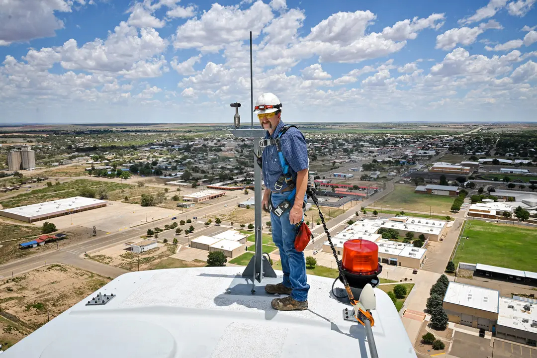 Terrill Stowe, técnico de aerogeneradores, de pie sobre la góndola, que alberga la caja de engranajes y el generador de un aerogenerador, en el campus del Mesalands Community College de Tucumcari, Nuevo México, el 11 de julio de 2024. (Andrew Marszal/AFP vía Getty Images)