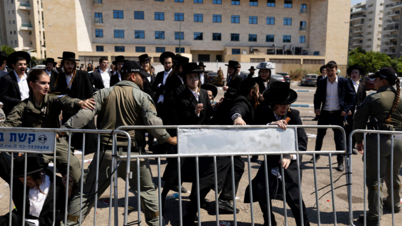 Hombres judíos ortodoxos chocan con agentes de policía durante una manifestación contra el reclutamiento en el ejército israelí cerca de una base de reclutamiento el 5 de agosto de 2024 en la zona de Tel HaShomer de Ramat Gan, Israel. (Amir Levy/Getty Images)