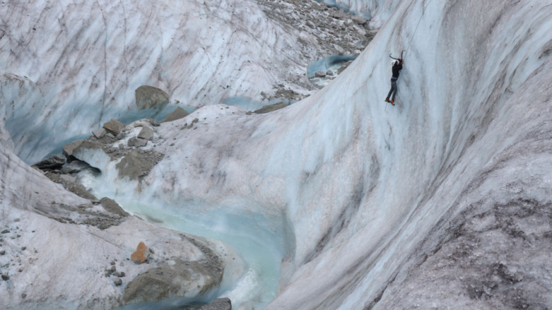 Un alpinista escala una pared de hielo por encima de un canal de agua de deshielo que está tallando el hielo de la Mer de Glace, el cuarto glaciar más grande de Europa y de 12 km de largo, en la cordillera del macizo del Mont Blanc el 01 de julio de 2024. (Sean Gallup/Getty Images)